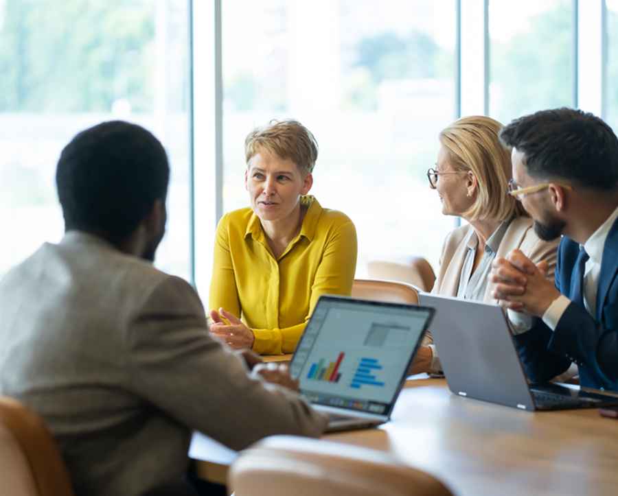 Colleagues sitting around a table with laptops discussing 