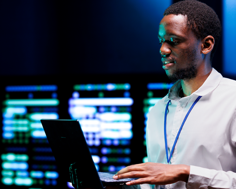 Man standing whilst holding a laptop in an IT setting